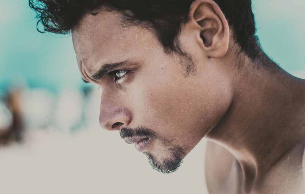 A close-up portrait of a young man looking thoughtfully into the distance.